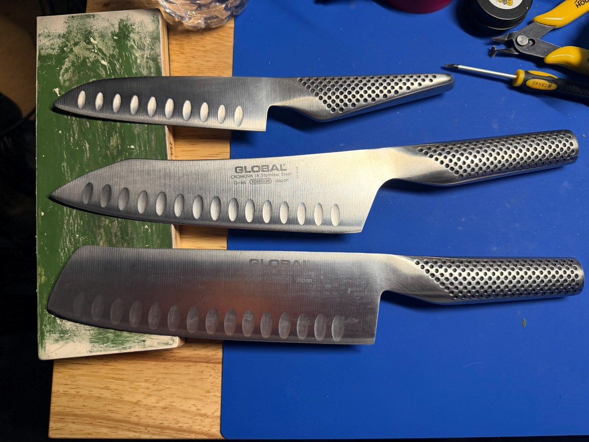 Three Global kitchen knives on sharpening workbench