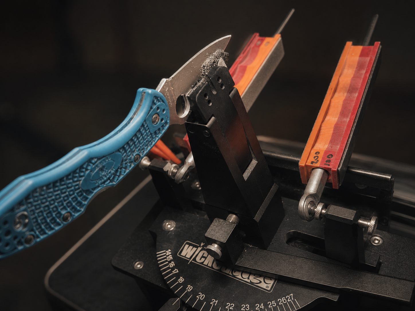 Blue handled folding knife being sharpened in guided sharpening system